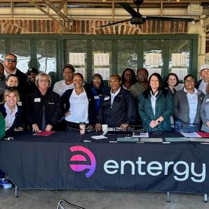 A group posed behind a table with "entergy" logo on the front.