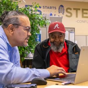 Two people seated in front of a laptop