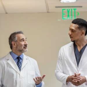 Two medical professionals talking and walking down a hallway.