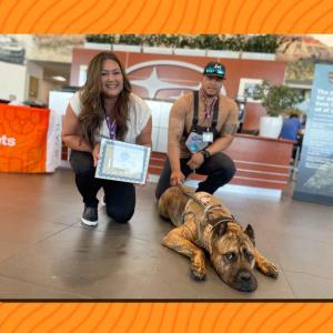 Two people with their dog and certificate of graduation.