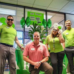 Employees in Green shirts in front of a poster that says "Green means GO"