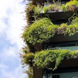 A multi-story building with overflowing plants on every balcony.