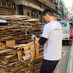 A person tying up a large bale of cardboard.