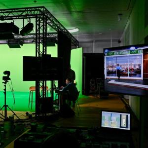 A person surrounded by green screens in a recording studio