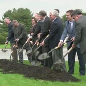 Group of people in suits using shovels to dig up some dirt