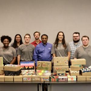 group of people behind a table of stacked shoe boxes