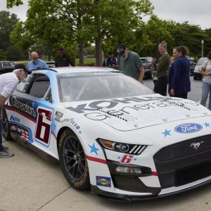 a group of people around a race car, some look in the windows