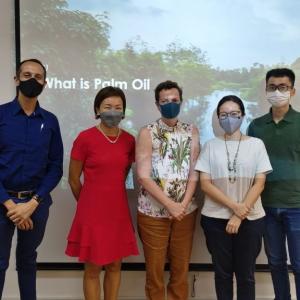 a group of 5 people stands in front of a screen with "what is palm oil" projected on it