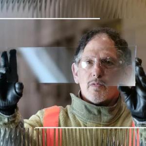 Dean looking through a raised, clear, piece of glass.