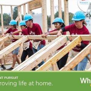Volunteers lifting up framing for a house with text "In constant pursuit of improving life at home" with the Whirlpool logo