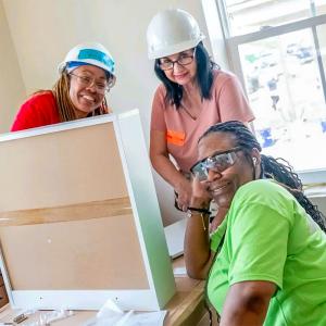 Three people putting together drawers inside a house.