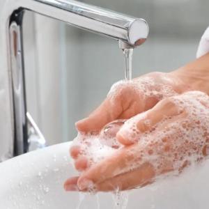 Close up of a person washing their hands in a sink.