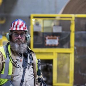 worker with a large beard in safety gear with an American Flag design on his helmet