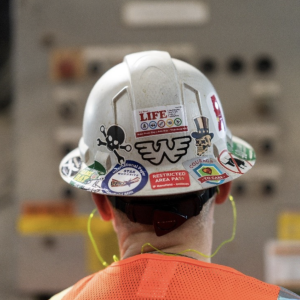the back of a worker's hard hat covered in stickers