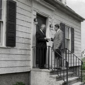Webster Bank Founder Harold Webster Smith (pictured right with hat in hand) delivers the bank’s first loan to Joe Baltrush in December 1935 on the steps of his home at 114 Chambers Street in Waterbury.