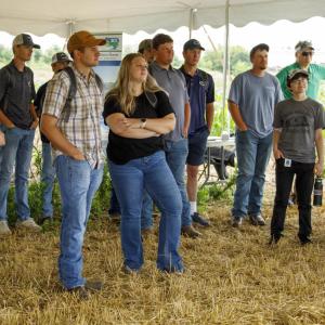 people watching a presentation outside under a tent