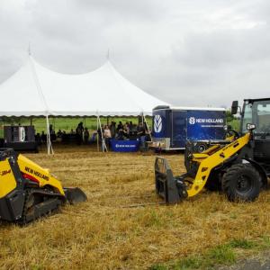 two yellow tractors outside with a tent in the background