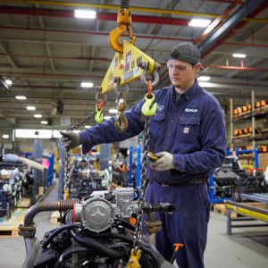 A person using a hoist to lift a piece of machinery