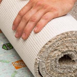 Beige Nike Grind carpeting being rolled out across floor with Home Depot and Nike logo's on floor base layer.