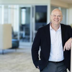 Ryan Schroeder leaning on a desk divider wall in an office setting.