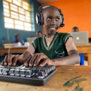 A smiling child with headphones using a computer.
