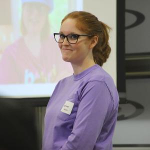 A smiling person in a purple shirt.