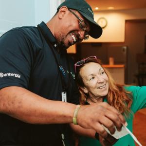 An Entergy employee helping a customer adjust a thermostat