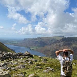 A person looking out at a vast hilly, wilderness area.