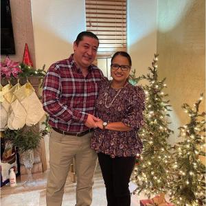 Martin and a woman holding hands in front of Christmas decorations