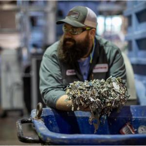A smiling person holding shredded textiles.