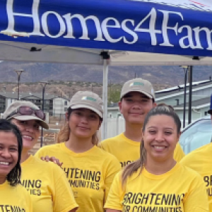 A group of volunteers posed in front of a Homes 4 families booth.