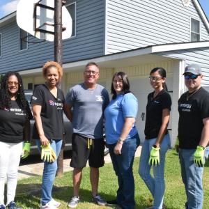 Six people posed next to a home outside.
