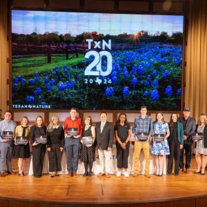 A group of honorees posed on stage with awards.