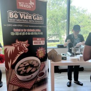 A sign for food in the foreground, with someone serving food in the background