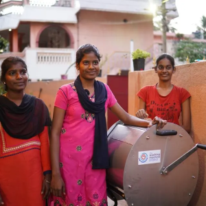 Three people standing next to a washing machine