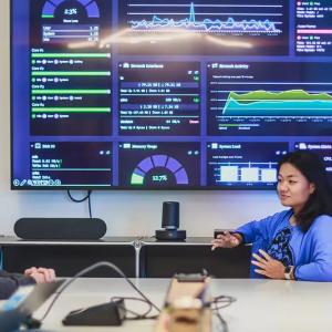People meeting and looking at multiple screens on a wall.
