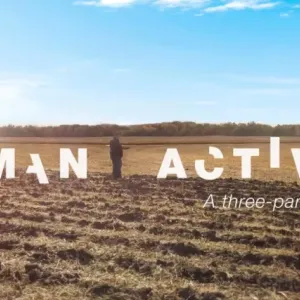 In white broken letters "Human activity". A person standing in a bare crop field, a blue sky above.