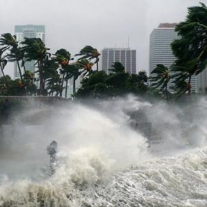 hurricane winds sending ocean waves into a city with palm trees