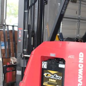 A person driving a forklift loaded with boxes.