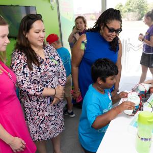 Two students and three adults conduct an experiment inside of the Curiosity Cube.