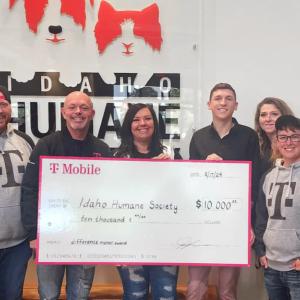 A small group posed with a large check in front of a sign "Idaho Humane"