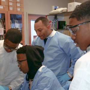 Dr. Arik King in the lab with the same group of young men of color. 
