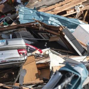 pile of wood, debris, and an overturned car
