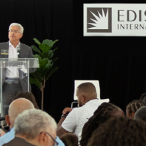 A person at a podium speaking to a seated crowd.