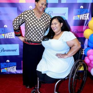 Two people pose on a red carpet. "Inclusion Week 2023" behind them.