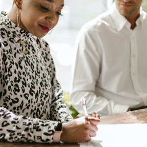 two people at a table, one writing on a piece of paper