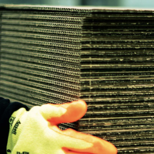 hand in an orange and yellow glove holding a stack of cardboard