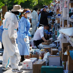 People in full ppe looking at shelves of boxes and other donations outside.