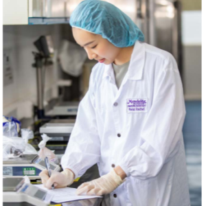 A person in protective lab gear making a note.