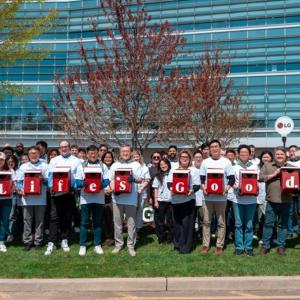 A group of people outside of a building, holding letters that spell "life's good."
